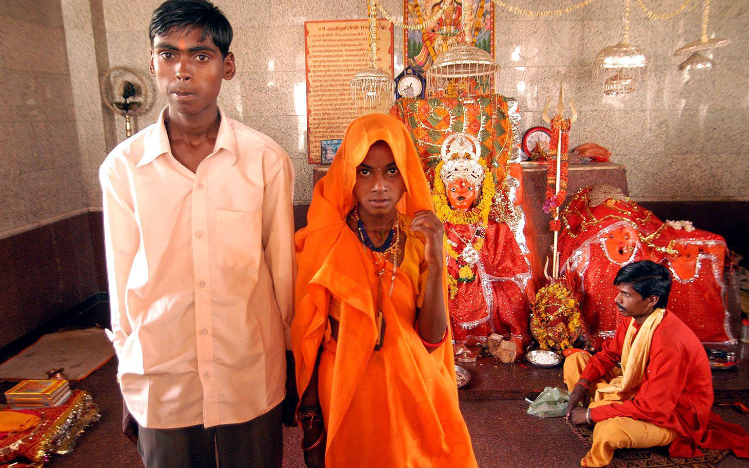 Eleven-year-old Anita, standing right, and her groom Birbal, 16, pose for a photograph after their marriage, as a priest looks on at Jalpa Mata temple in Rajgarh, about 155 kilometers (96 miles), northwest of Bhopal, India, Sunday, April, 30, 2006. Ignoring laws that ban child marriages, hundreds of children, some as young as seven years old, were married in a centuries-old custom across central and western India this week, according to news reports. (AP Photo/Prakash Hatvalne)