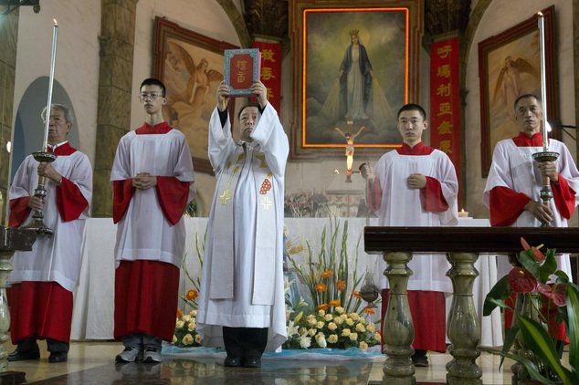 A Chinese priest holds up a bible during a mass at the 400-year-old Cathedral of the Immaculate Conception in Beijing, China, Friday, Aug. 15, 2014. Chinese Catholics on Friday cheered Pope Francis visit to neighboring South Korea, saying they hoped his trip to their region would help end the estrangement between Beijing and the Vatican. However, Chinas entirely state-run media imposed a virtual news blackout on his visit, ensuring the public at large would know little about Francis activities. (AP Photo/Ng Han Guan)